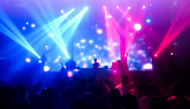 DJ turns music people dancing in night club with beautiful light, women and men in the happy fun.photo blur