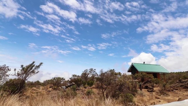 Time lapse shot of a cabin, plants and nature, Clouds moving in a blue sky, on mount Kilimanjaro, on a sunny day, in Tanzania, Africa