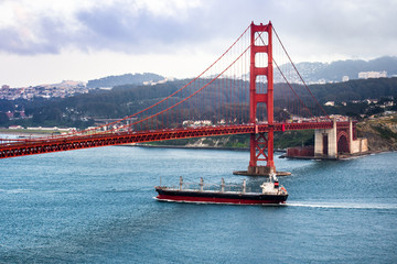 Large cargo ship travelling under Golden Gate Bridge, San Francisco bay area, California