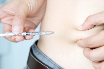 Hand of a man with diabetes He is using a syringe. At his belly.health and medical concepts.