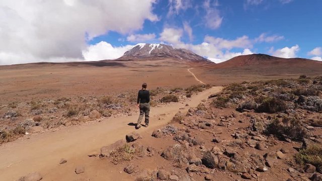 Static shot of a woman hiking, towards the summit of mount Kilimanjaro, on a sunny day, near Horombo hut, in Tanzania, Africa