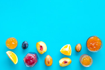 Jams different tastes made of fruits and berries near pieces of fruits on blue background top view space for text