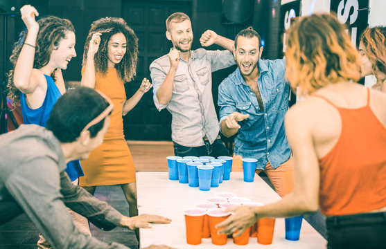 Happy friends playing beer pong in youth hostel - Travel and joy concept with backpackers having unplugged fun at guesthouse - Young people on playful genuine attitude - Teal and orange filter