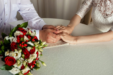 Obraz na płótnie Canvas Hands and rings of just married couple with wedding bouquet in soft-focus in the background. newlyweds hands with rings.