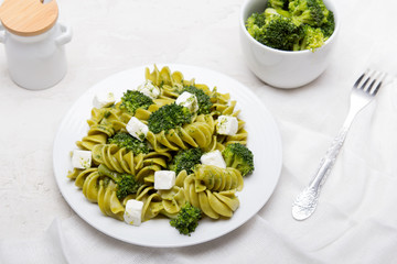 Tasty dinner. Green  pasta with broccoli, feta cheese and herb sauce on a white background.