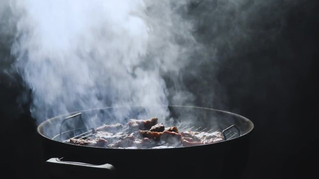 Opening the grill and letting the smoke go out from under the lid cover isloated on black background