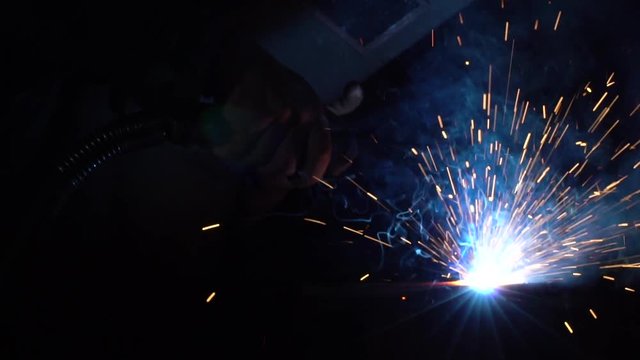 welding iron pieces while creating blue sparks