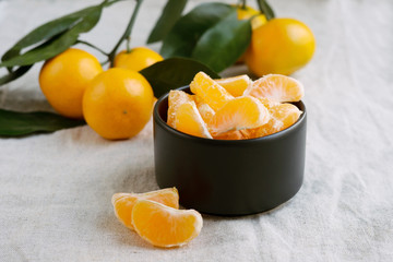 Slices of mandarine in black bowl. Peeled tangerine
