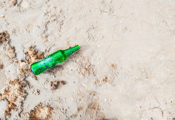 Green empty glass bottle in the sands. Thirst, search for water