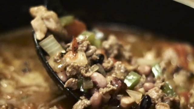 chili is being made for dinner. the food is prepare with black bean, pinto beans pork diced meats such as beef steak. the chef even add tomato celery onions garlic to the stew for added flavor. 