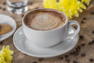 cup of cappuccino coffee for breakfast on a white saucer with cookies