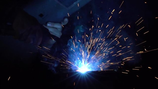 welding iron pieces while creating blue sparks