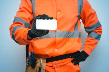 Builder worker is holding in hand a blank screen mobile phone. Call to a repair man concept....