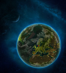 Denmark from space on Earth at night surrounded by space with Moon and Milky Way. Detailed planet with city lights and clouds.
