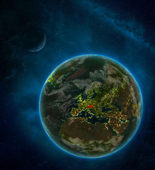 Austria from space on Earth at night surrounded by space with Moon and Milky Way. Detailed planet with city lights and clouds.