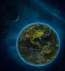 Honduras from space on Earth at night surrounded by space with Moon and Milky Way. Detailed planet with city lights and clouds.