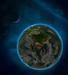 Uruguay from space on Earth at night surrounded by space with Moon and Milky Way. Detailed planet with city lights and clouds.