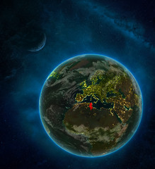 Tunisia from space on Earth at night surrounded by space with Moon and Milky Way. Detailed planet with city lights and clouds.