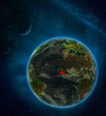 Guinea from space on Earth at night surrounded by space with Moon and Milky Way. Detailed planet with city lights and clouds.