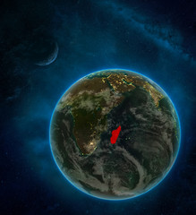 Madagascar from space on Earth at night surrounded by space with Moon and Milky Way. Detailed planet with city lights and clouds.