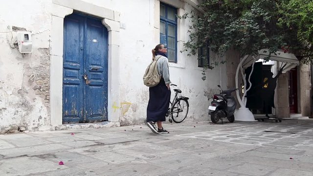Young woman with a backpack is walking down the street at the old city of Kos, Greece.