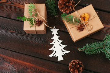 Christmas composition. Christmas gift, knitted blanket, pine cones, fir branches on wooden background.