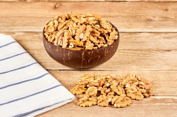 Peeled walnuts in the brown bowl and white napkin on wooden table with copy space, close-up
