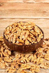 Peeled walnuts in the brown bowl on wooden table with copy space, close-up