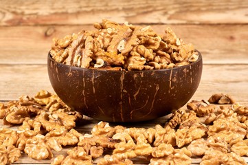 Peeled walnuts in the brown bowl on wooden table with copy space, close-up