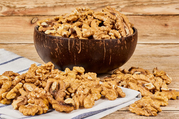 Peeled walnuts in the brown bowl and white napkin on wooden table with copy space, close-up