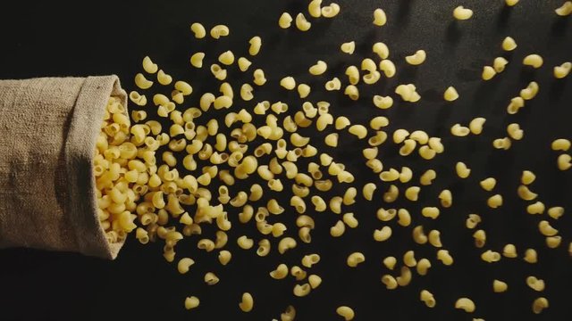 TOP VIEW: Bag falls and lumaconi pasta are poured out of it - Slow Motion
