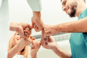 Medical service teamwork - Doctor, surgeon and nurse join hands together.