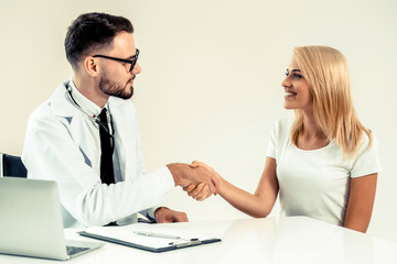 Male doctor doing handshake with female patient in hospital office. Healthcare and medical service.