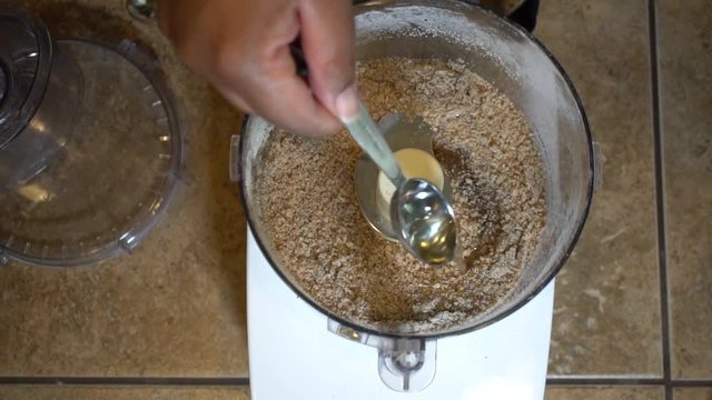 Adding tablespoon of coconut oil to dry ingredients in food processor, SLOWMO