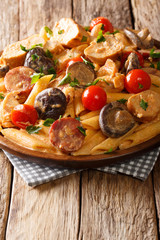 Penne pasta with chicken, mushrooms, smoked sausage, covered with cream cheese sauce close-up. vertical