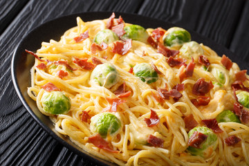 Hot spaghetti cooked with Brussels sprouts, bacon, garlic covered with creamy cheese sauce close-up on a plate. horizontal