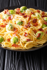 Delicious tender Italian spaghetti with brussels sprouts, ham with creamy cheese sauce close-up. vertical