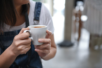 Woman wearing a bib holding coffee two hands.