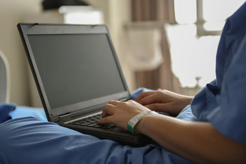 Sick woman using laptop to work on the bed.