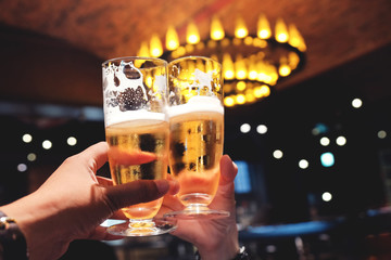 Couple or Friend making Cheers with a Glass of Beer to Celebrate in Restaurant,Bar or Cafe, Image for Oktoberfest or any Cheerful Event Concept, Night Scene