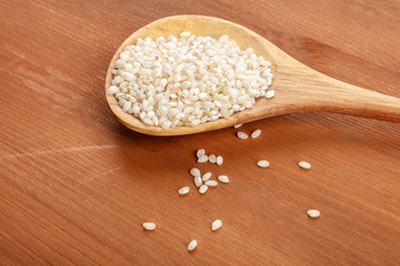 A closeup photo of Spanish calasparra rice used for paella in a wooden spoon on a rustic background with copy space