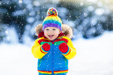 Child playing with snow in winter. Kids outdoors.