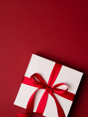Top view of gift box with red ribbon over red background