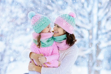 Mother and child in knitted winter hats in snow.