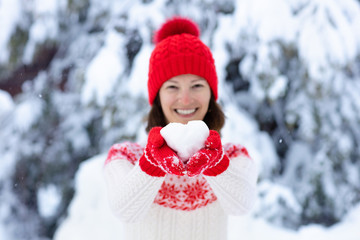 Young woman in knitted sweater with snow heart