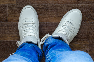 blue jeans and white sports sneakers on man's legs