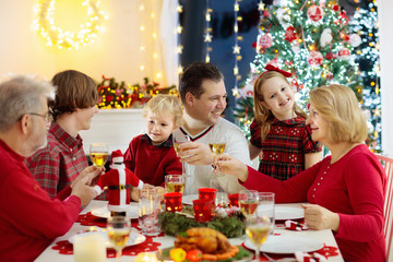 Family with kids having Christmas dinner at tree