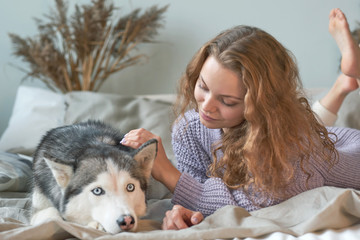 redhead woman relaxing at home with her pet dog Husky