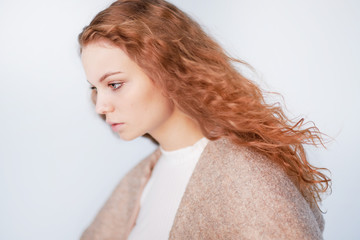 Beautiful girl dressed in french style on a white background. red hair woman is wrapped in a coat, winter clothes. Smiling lady wearing warm clothes, winter portrait