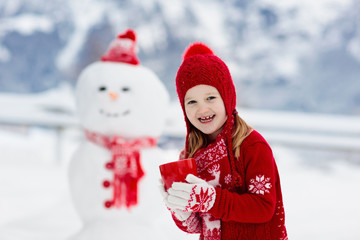 Child building snowman. Kids build snow man.